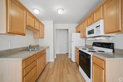 A kitchen with wooden cabinets and a white fridge.