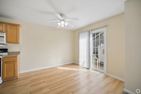 A room with a ceiling fan and sliding glass doors.