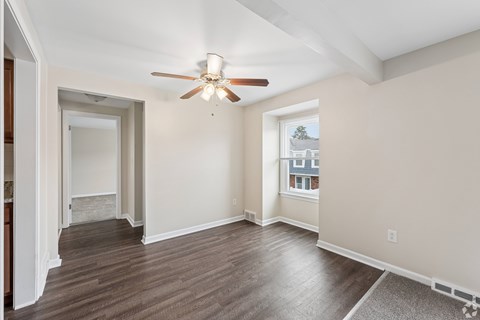 A room with a ceiling fan and wooden flooring.