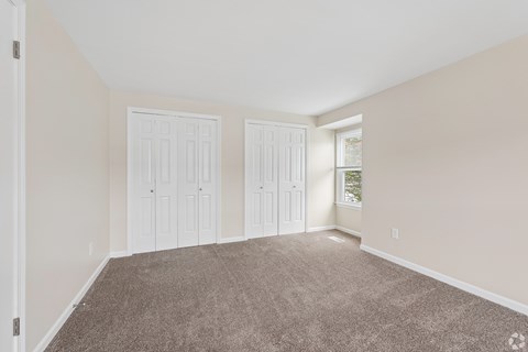 A room with carpeted floor and white doors.