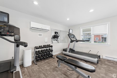 A home gym with a treadmill, weights, and exercise equipment.
