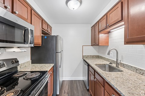 A kitchen with a black stove top oven, a black refrigerator, and brown cabinets.