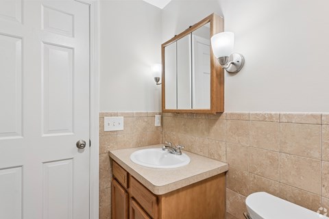 A bathroom with a sink, mirror, and bathtub.