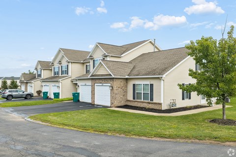 A house with a driveway and a tree in front.