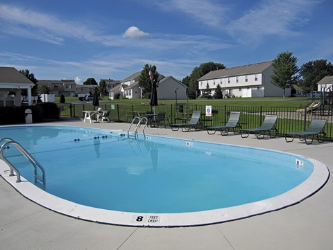 A large outdoor swimming pool with a white fence around it.