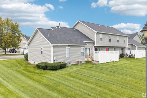 A large house with a grey roof and a white fence.