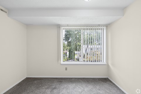 A room with a window covered by a white blind.