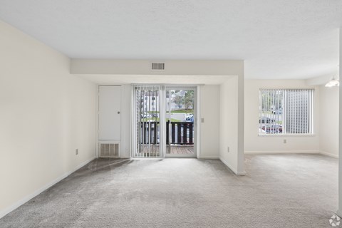 A spacious, empty room with a carpeted floor and white walls.