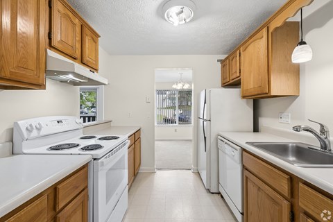 A kitchen with white appliances and wooden cabinets.