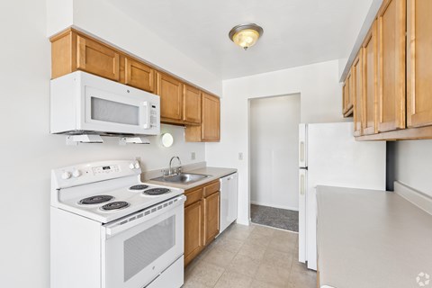 A kitchen with white appliances and wooden cabinets.