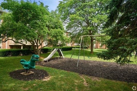 A playground with a green slide and a brown mulch area.