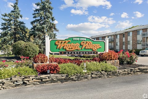 A sign for a community named "Wain Village Apartments" is displayed in front of a building.