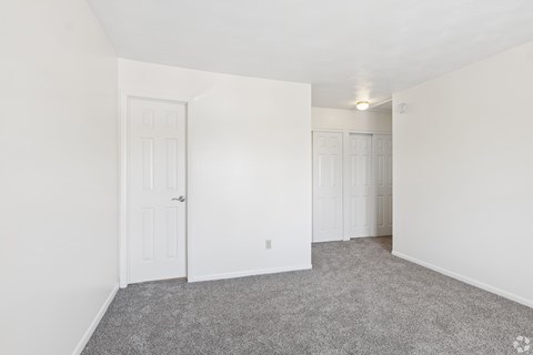 A room with two doors and carpeted floor.