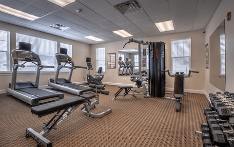 A gym with a variety of equipment including treadmills, weights, and exercise machines.