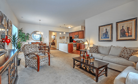 A living room with a grey couch, a wooden coffee table, and a dining table with chairs.