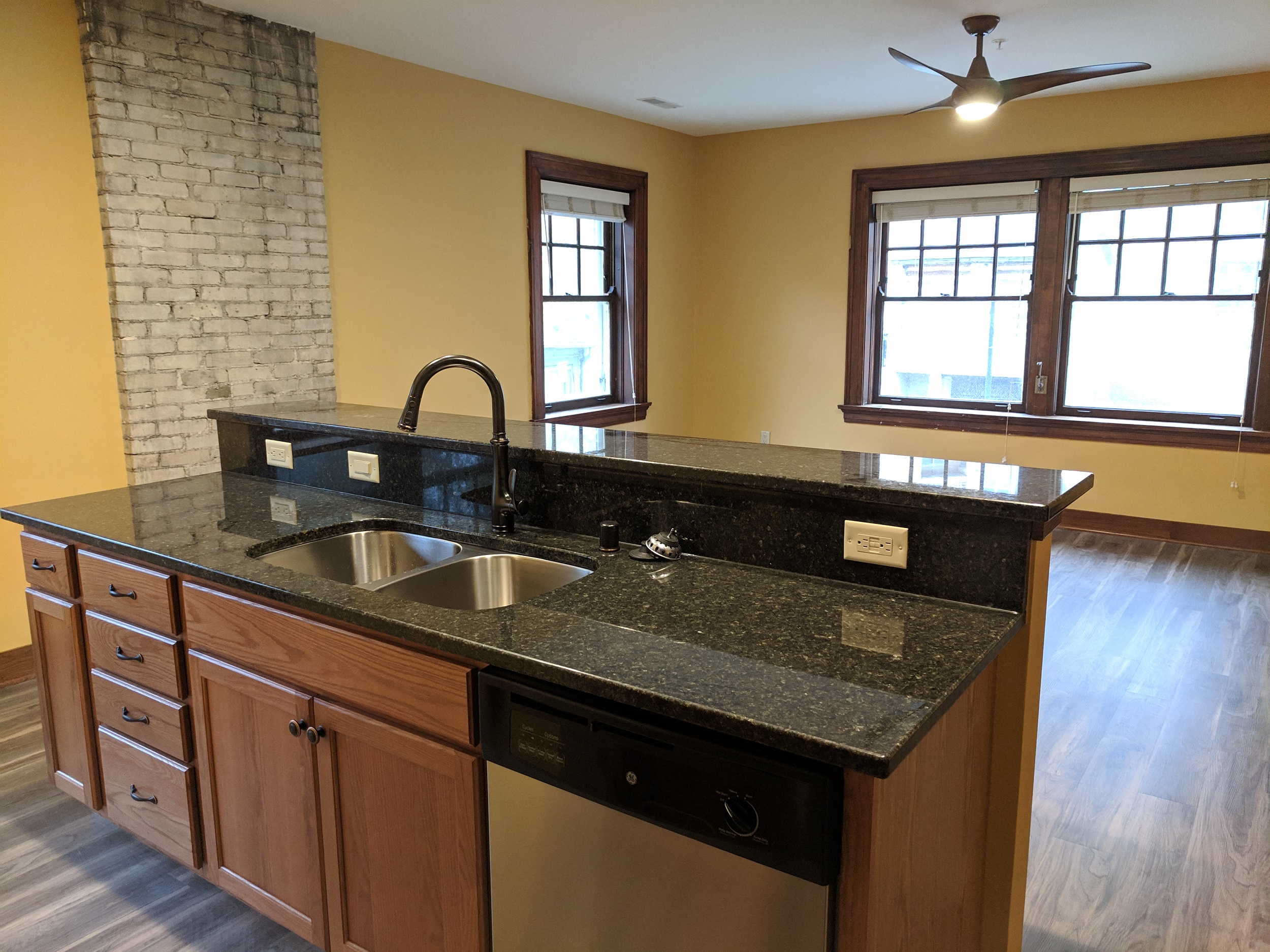 A kitchen with a black granite countertop and wooden cabinets.