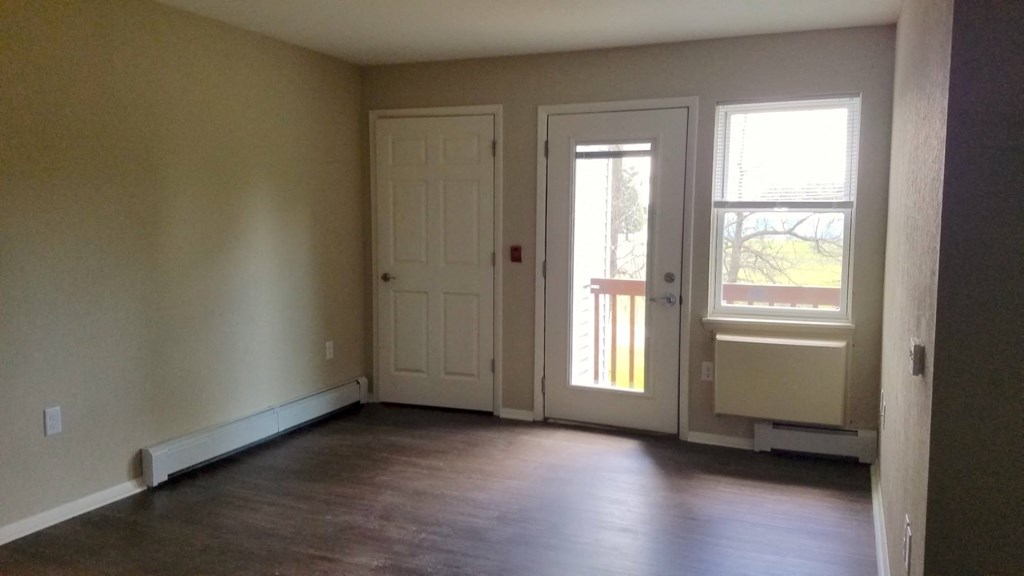 an empty living room with two doors and a wood floor