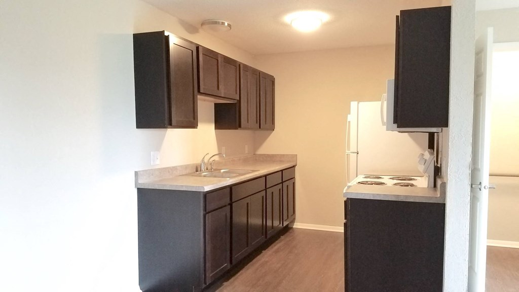 an empty kitchen with black cabinets and a white refrigerator