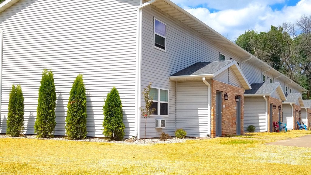 the front of a white house with a yard and trees