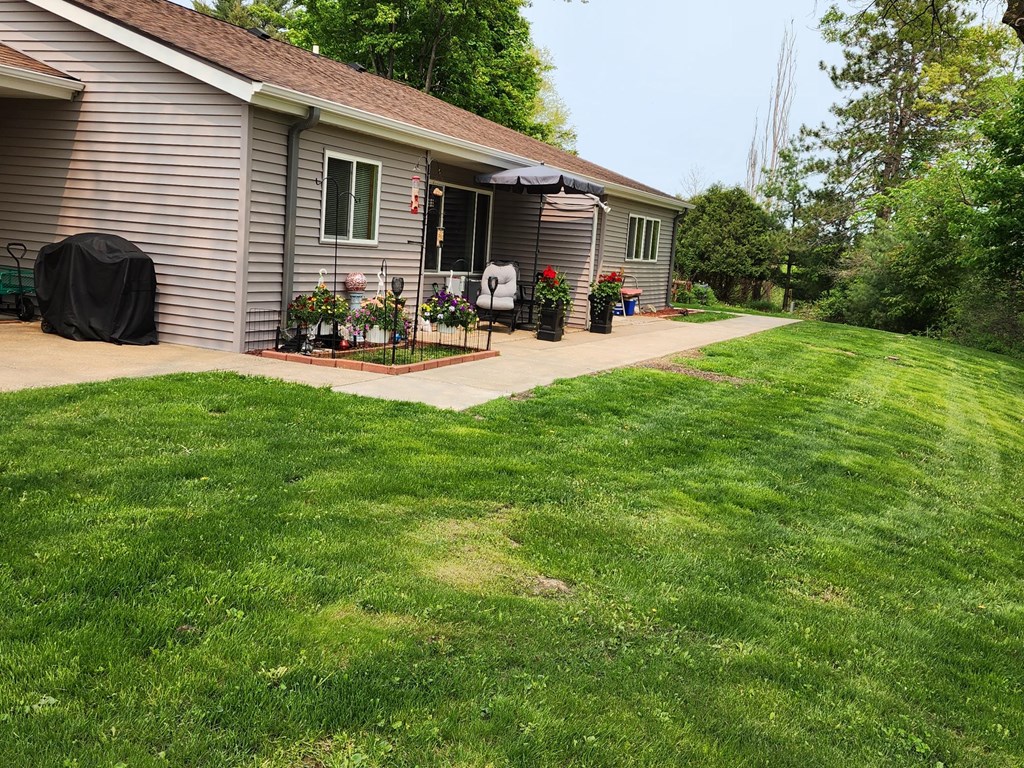 a backyard with green grass and a gray house