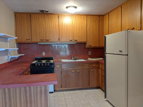 A kitchen with wooden cabinets and a refrigerator.