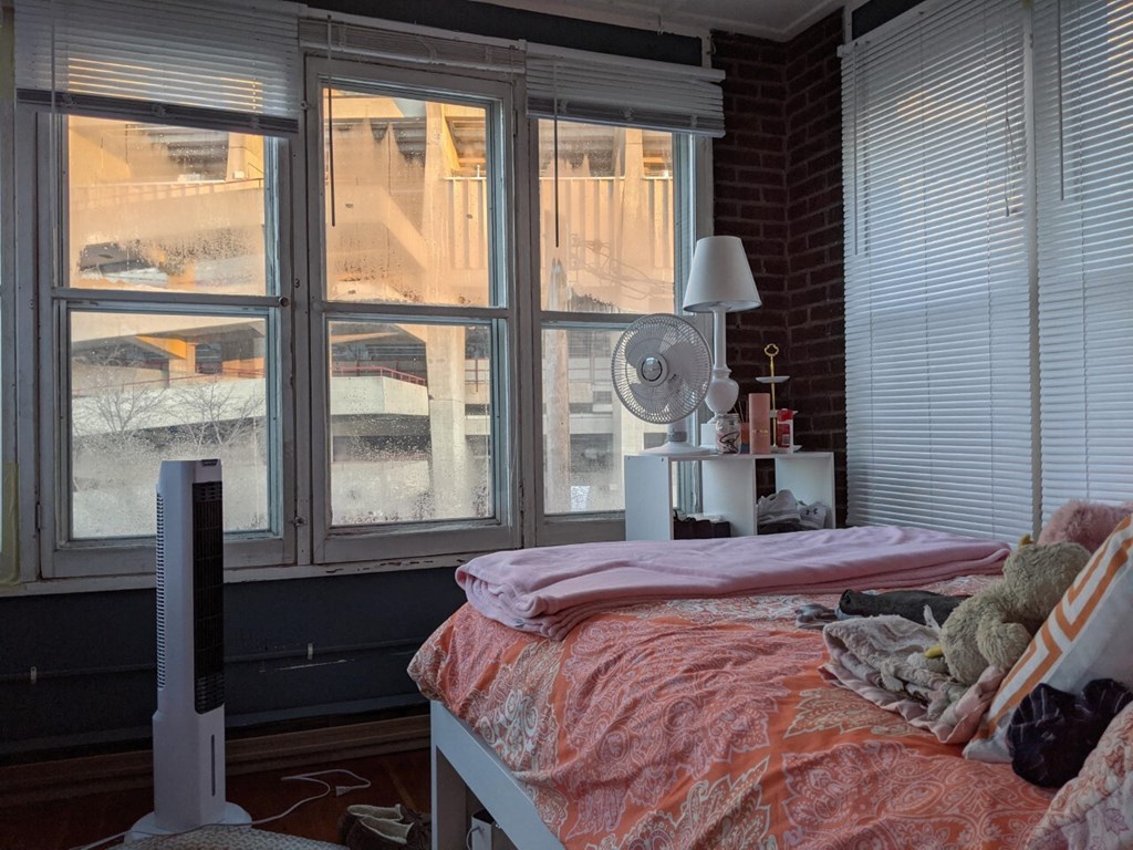 A bedroom with a bed, a fan, and a window with a view of a snowy landscape.