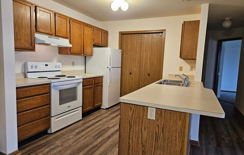 A kitchen with wooden cabinets and a white stove top oven.