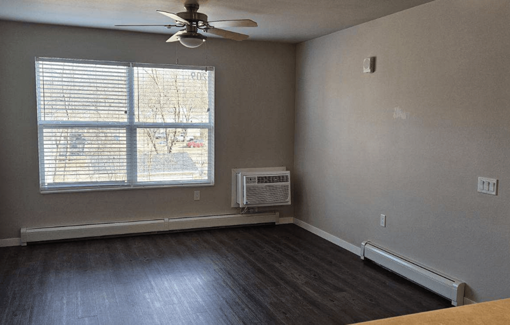 an empty living room with  aceiling fan and a window