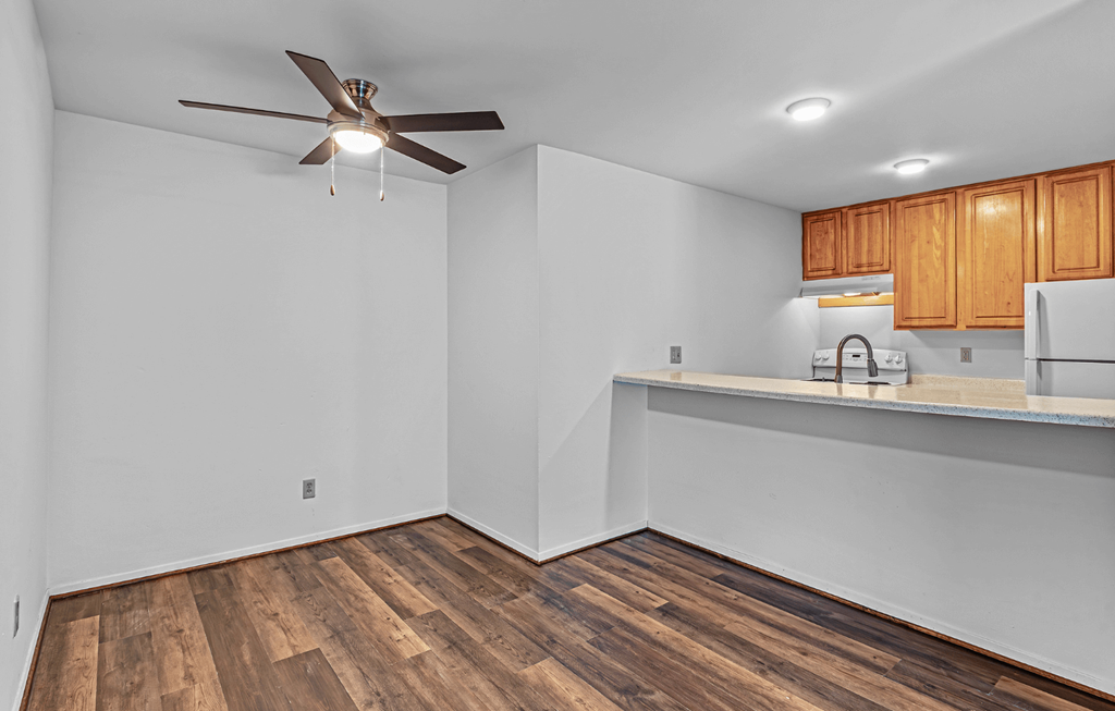 A room with a ceiling fan and wooden floors.