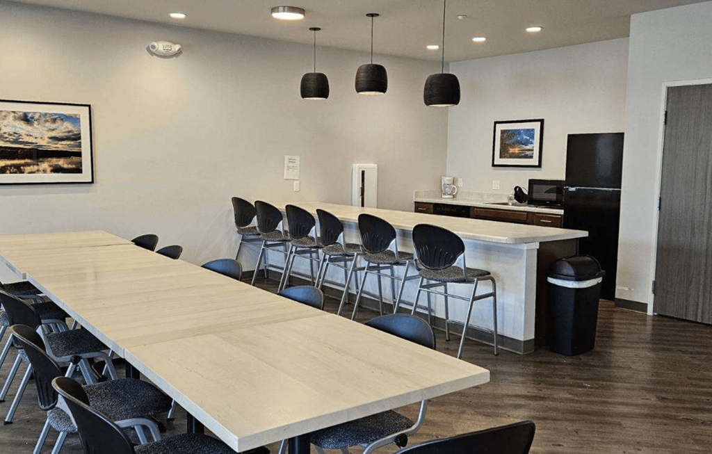 a conference room with a long table and chairs and a kitchen