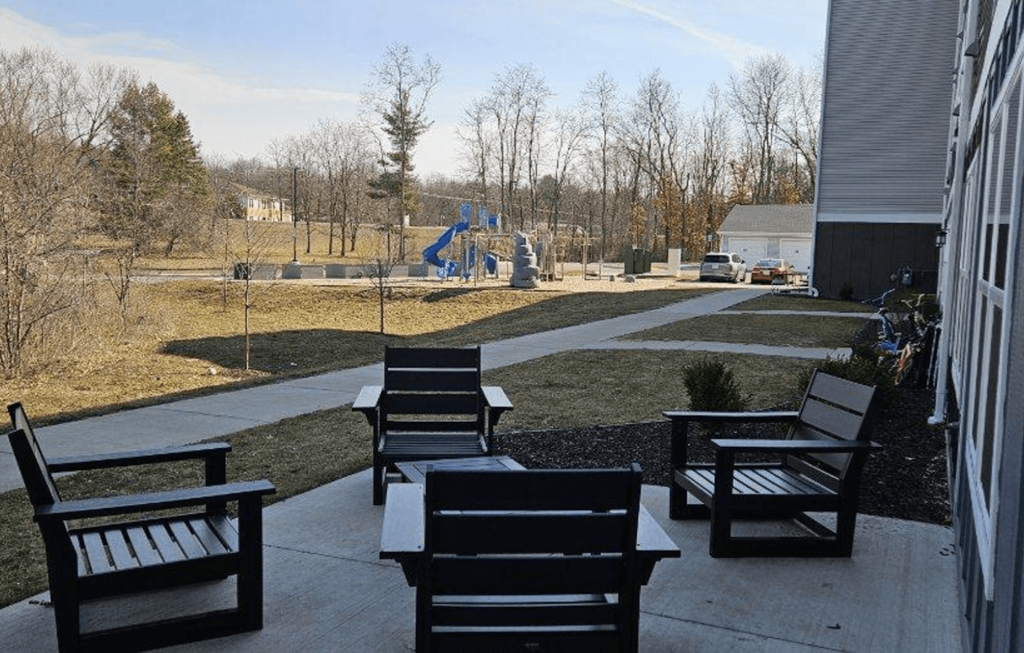 a patio with benches and a playground in the background