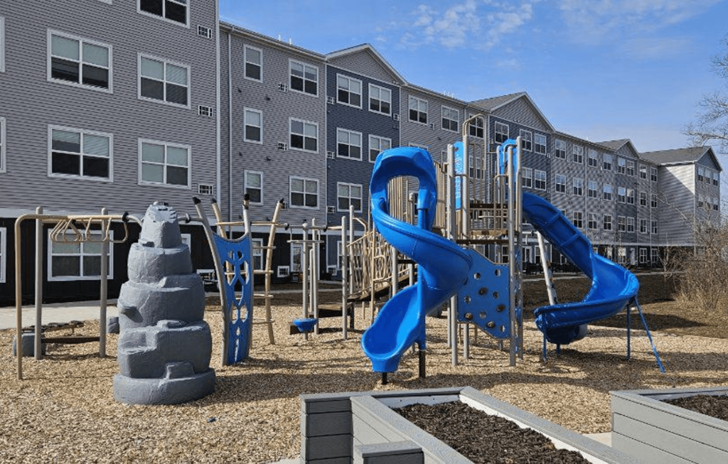 We have a large playground with slides and other playground equipment in front of an apartment building