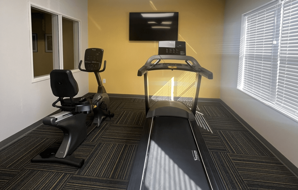 the fitness center has a treadmill and a tv