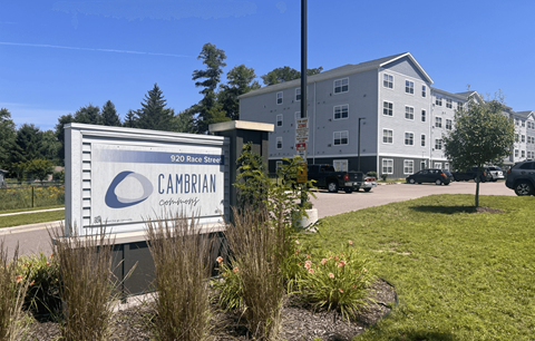 A Cambrian Community sign is in front of a building.