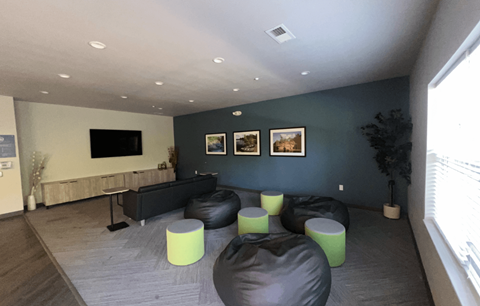 A living room with a black couch and green ottomans.