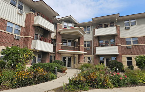A multi-story apartment building with a landscaped courtyard in front.