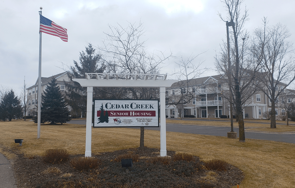 the sign for cedar creek in front of a building with an flag