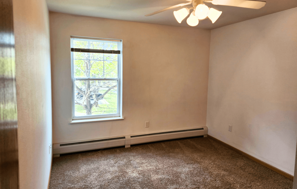A room with a window and a ceiling fan.