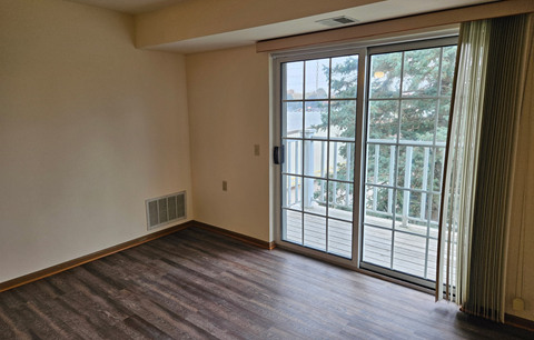 A room with a sliding glass door leading to a balcony.