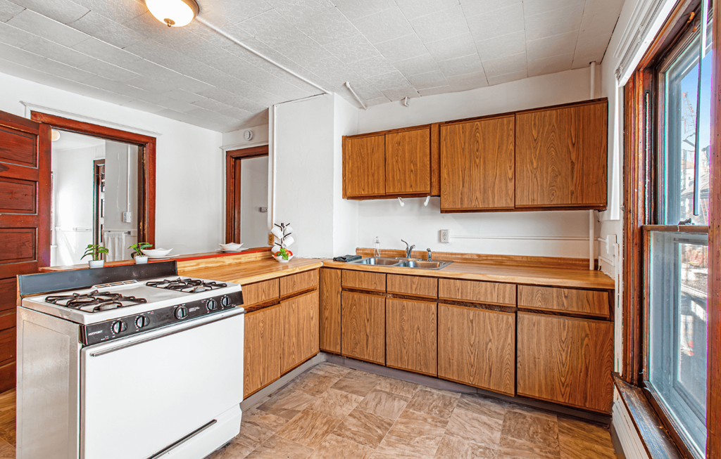 A kitchen with wooden cabinets and a white stove top oven.