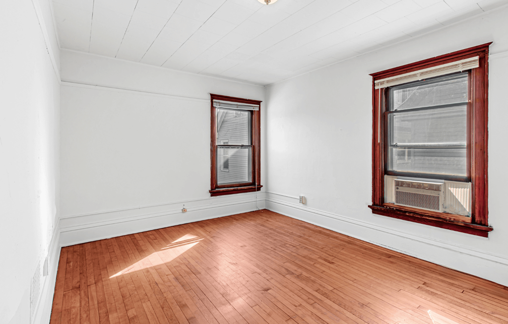 A room with wooden floors and two windows.