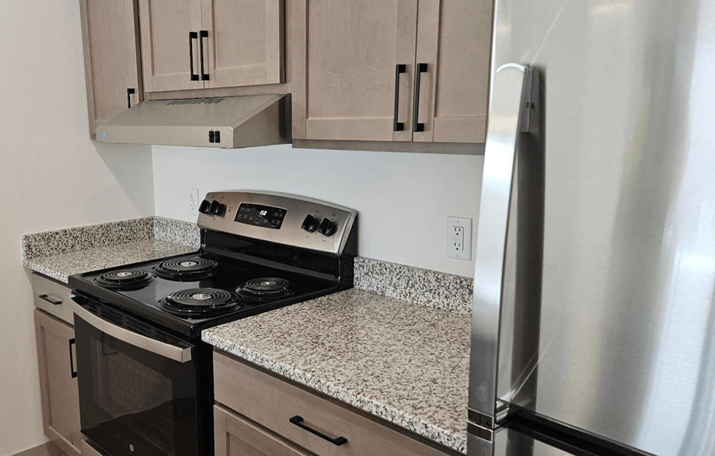 A kitchen with a stove top oven and a refrigerator.