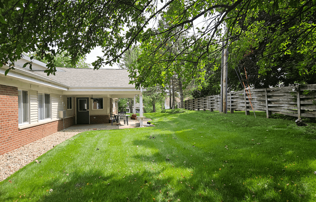 a backyard with green grass and a brick house