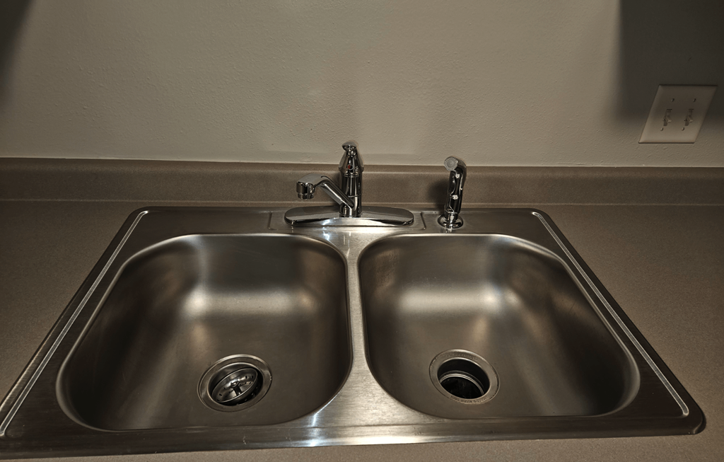 a kitchen sink with two faucets