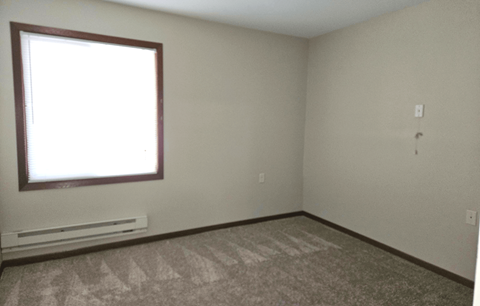 an empty room with a window and a radiator