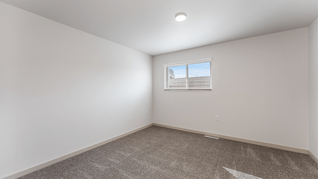 A room with a carpeted floor and a window with blinds.