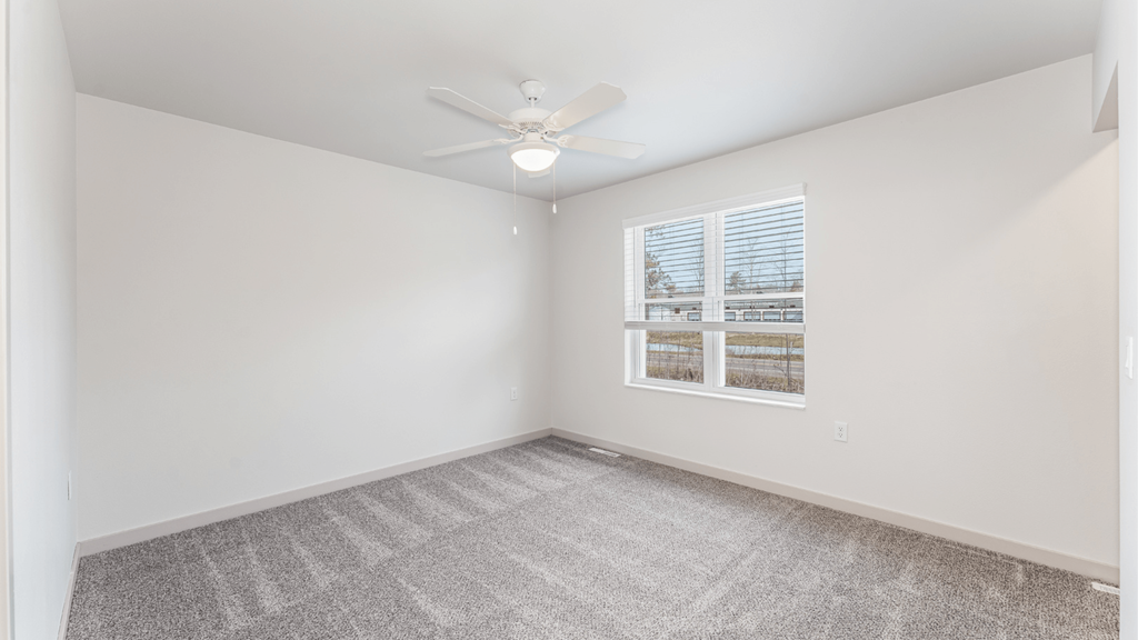 A room with a ceiling fan and a window with blinds.