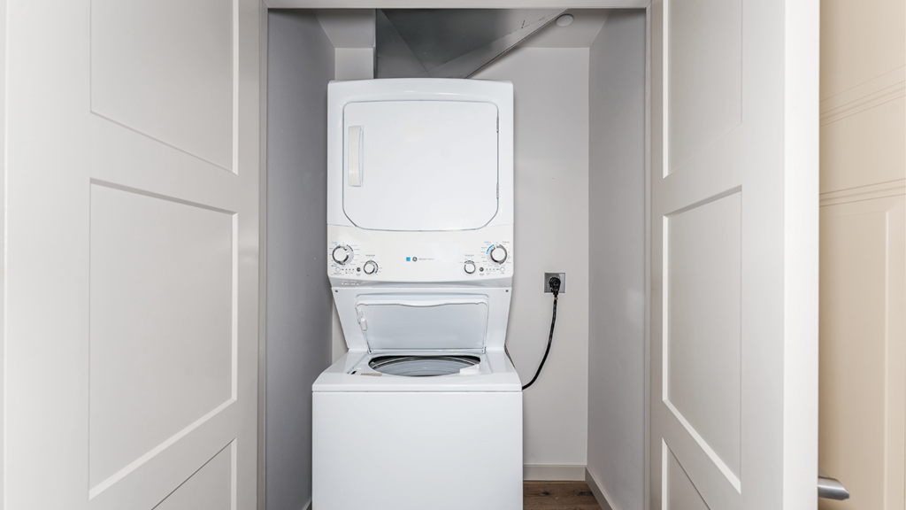 A white washing machine is in a small alcove.
