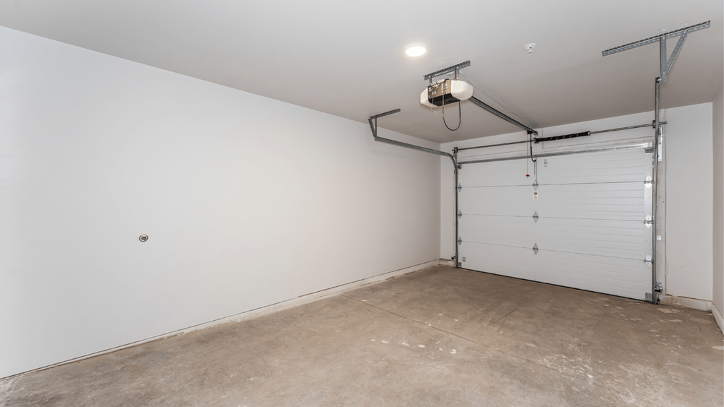 A garage with a white door and a concrete floor.