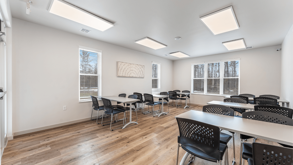 A room with tables and chairs and a painting on the wall.